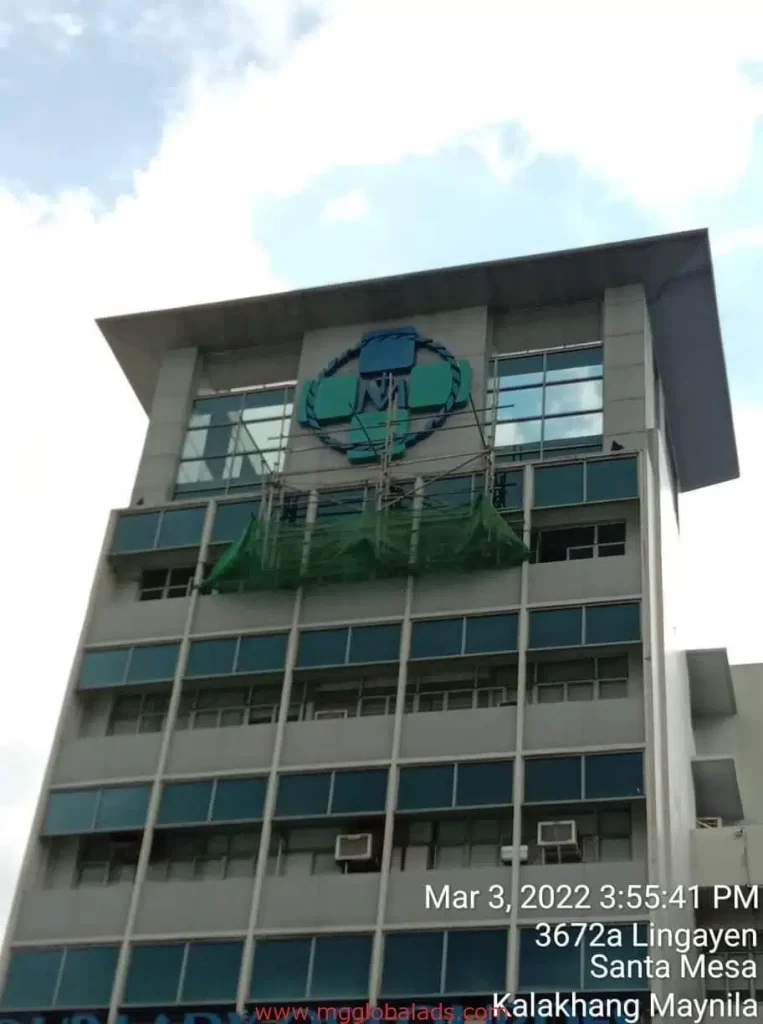 Medical building signage with blue and green logo, window units, green safety net in Makati by M&G Global Ads.