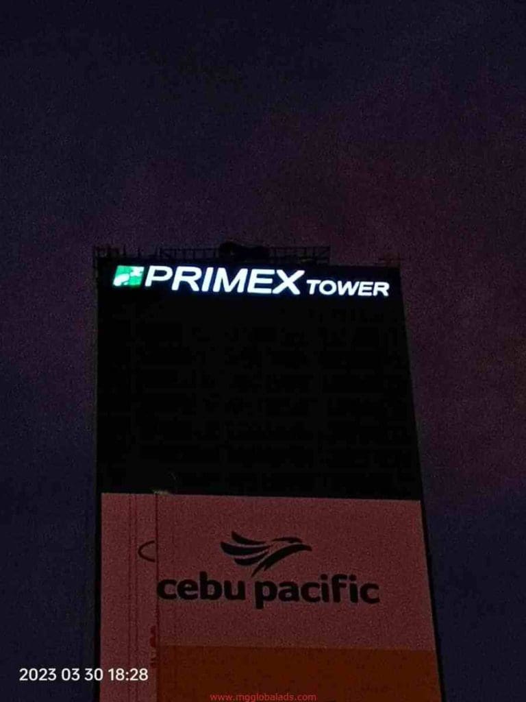 Illuminated PRIMEX TOWER building signage and Cebu Pacific ad in Ortigas at night, timestamped 2023-03-30, by M&G Global Ads.