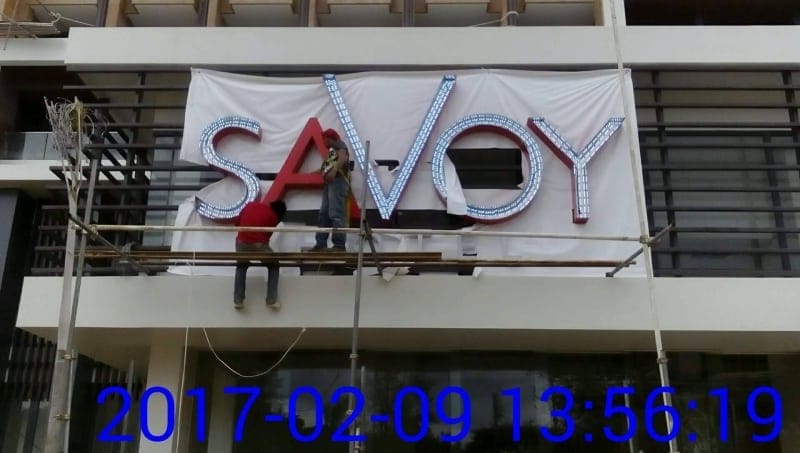 Illuminated SAVOY acrylic signage installation by workers on scaffolding, Makati building exterior, by M&G Global Ads.