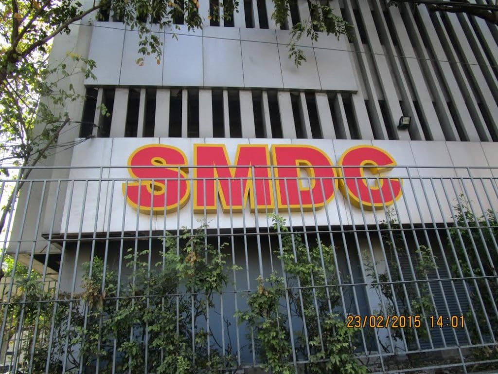 SMDC channel letter signage on a building facade in Ortigas, with metal fence and greenery, by M&G Global Ads.