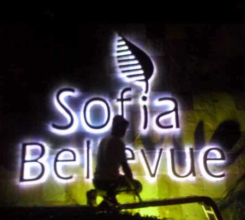 Illuminated Sofia Bellevue stainless signage with leaf design, night view, in Makati. Person silhouetted in front. By M&G Global Ads.