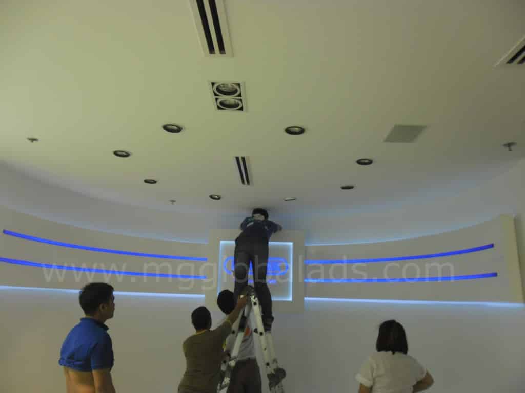 Team installs indoor acrylic signage for client in a modern Makati room with blue accent lighting by M&G Global Ads.