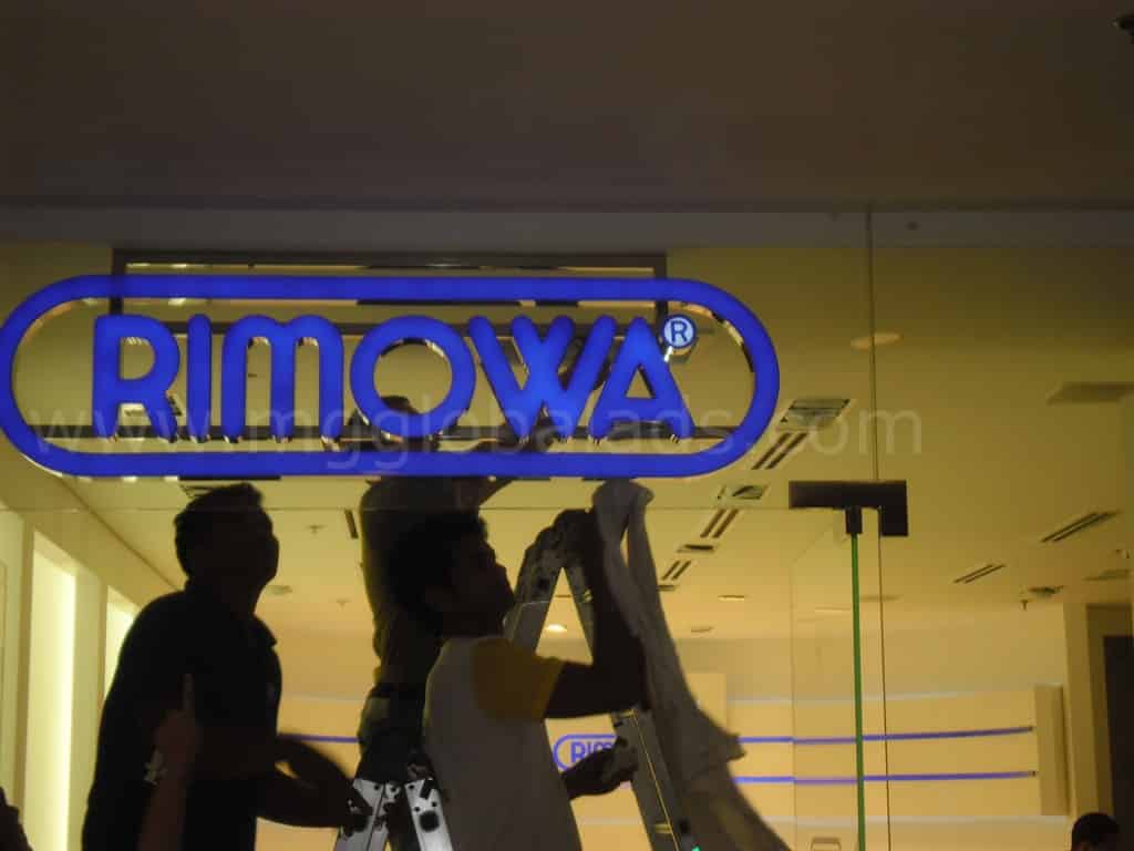 RIMOWA LED building signage installation in a modern Makati store, ladder setup by two staff. By M&G Global Ads.