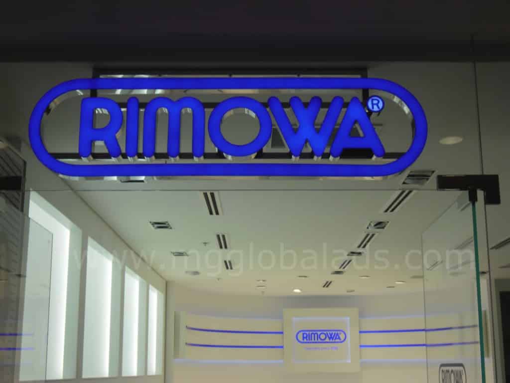 Illuminated acrylic RIMOWA signage at store entrance in Makati with glass reflections, by M&G Global Ads.