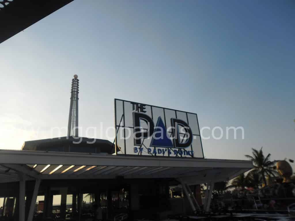 Pylon signage for THE PAD BY DAY & SON atop a building with guitar structure and palm trees in Quezon City by M&G Global Ads.