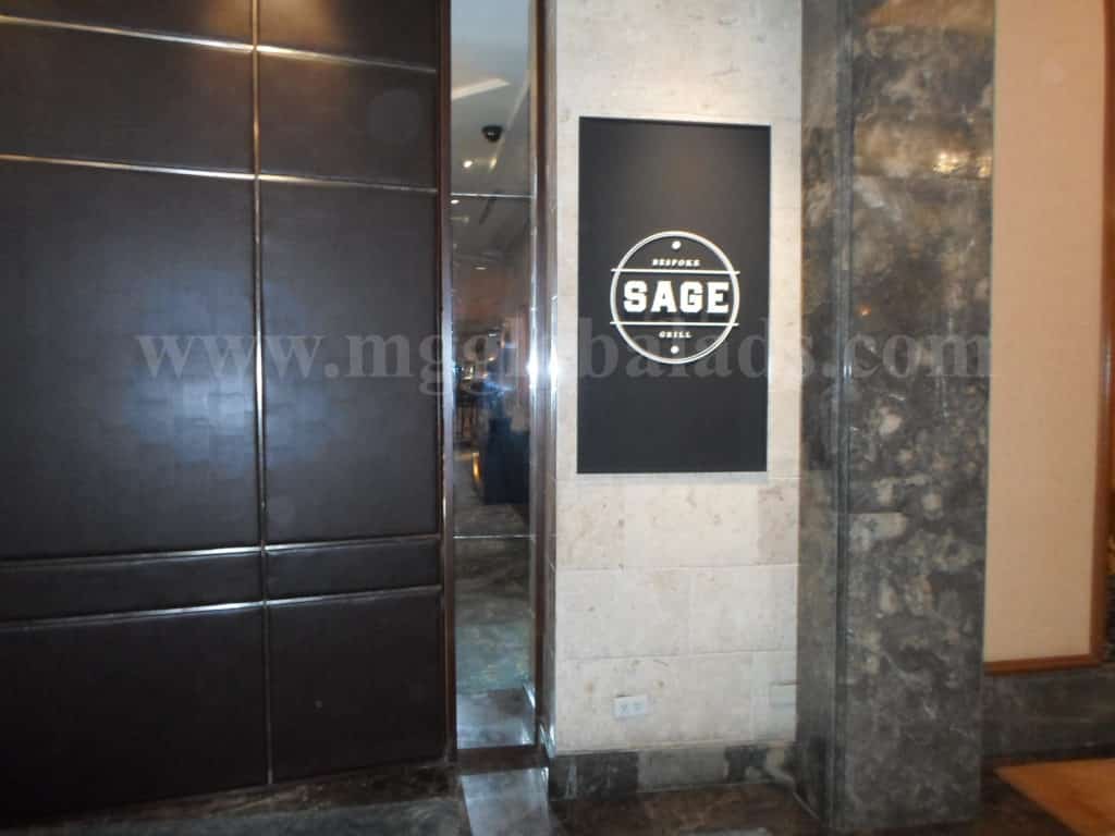 Indoor acrylic office signage SAGE on marble wall near door in a modern Makati building interior by M&G Global Ads.