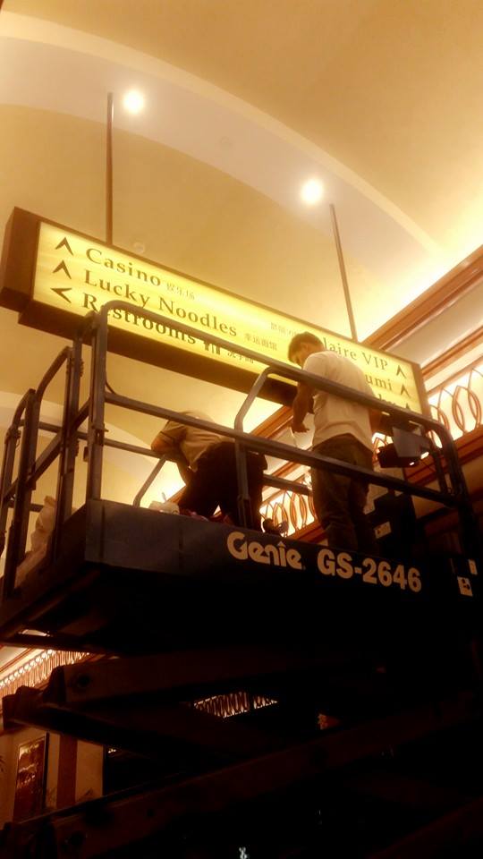 Acrylic directional signage install for casino client in Makati, with workers on lift—by M&G Global Ads.