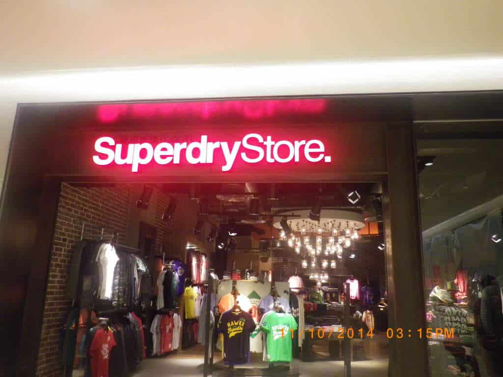 Superdry Store entrance with red and white acrylic signage in BGC, showing clothing displays and lighting by M&G Global Ads.