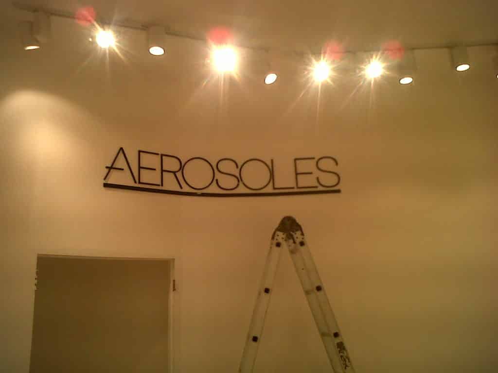 Acrylic indoor signage installation in Makati with ladder and white wall under spotlights by M&G Global Ads.