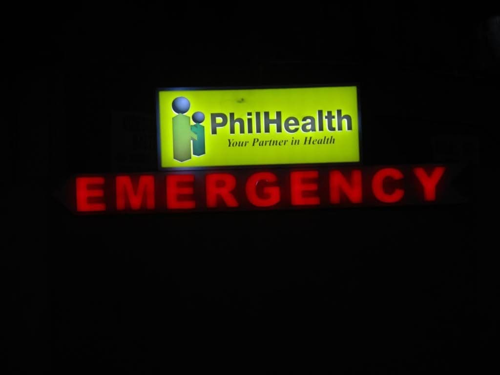 Lit acrylic emergency signage for PhilHealth with logo and red arrow in Quezon City healthcare facility by M&G Global Ads.
