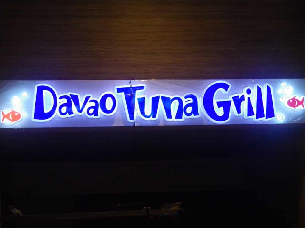 Acrylic signage for Davao Tuna Grill in blue and white with red fish, wood background, Makati. By M&G Global Ads.