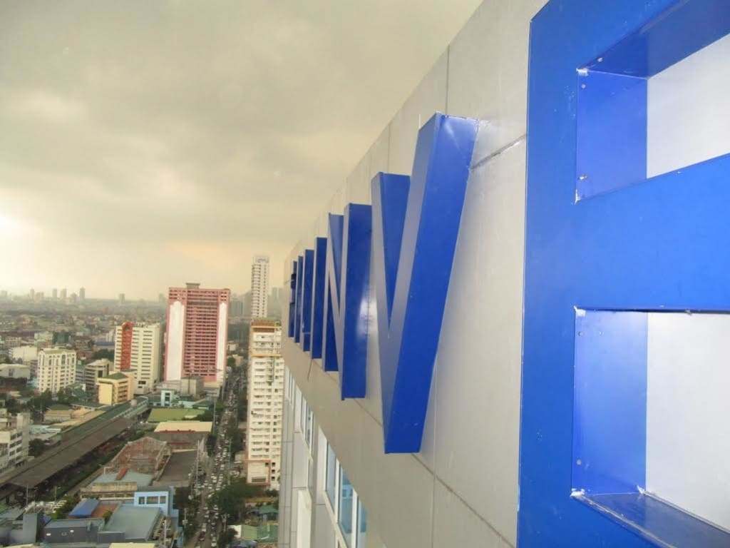 Large blue billboard signage on tall building in Makati with cityscape view under cloudy sky by M&G Global Ads.