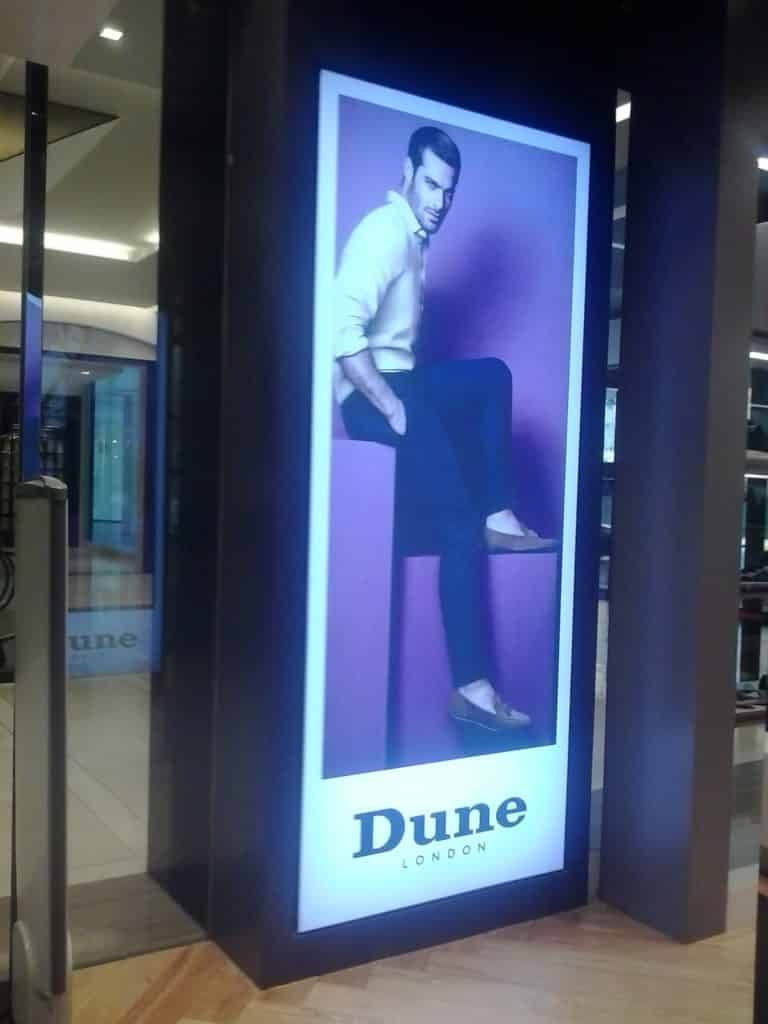 Backlit indoor signage for Dune London, store display in Makati with man on purple block, vibrant look by M&G Global Ads.
