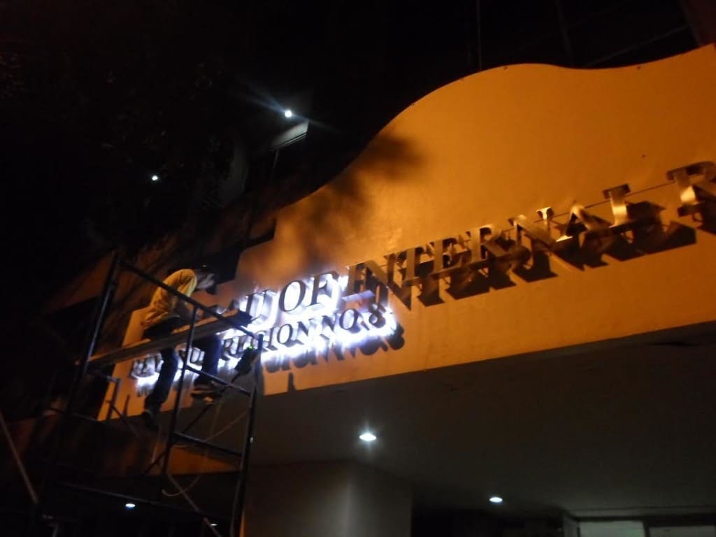 Illuminated acrylic signage installation at night on building exterior in Ortigas by M&G Global Ads.