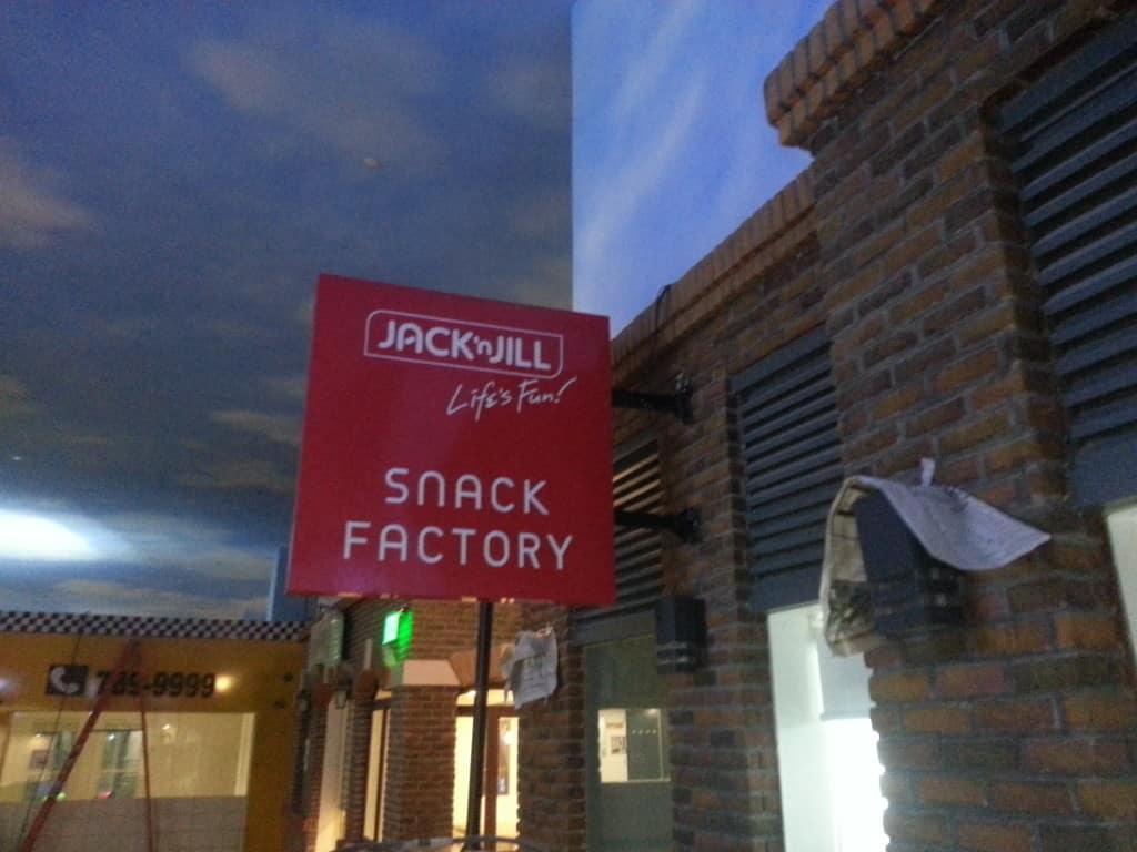 Jack n Jill Lifes Fun! SNACK FACTORY outdoor signage on brick wall in Quezon City under cloudy sky by M&G Global Ads.