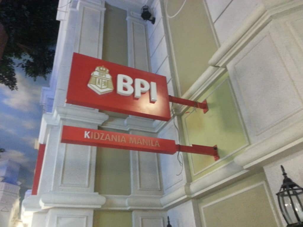 Red acrylic BPL signage with Kidzania Manila logo on yellow building in Ortigas, featuring white columns by M&G Global Ads.