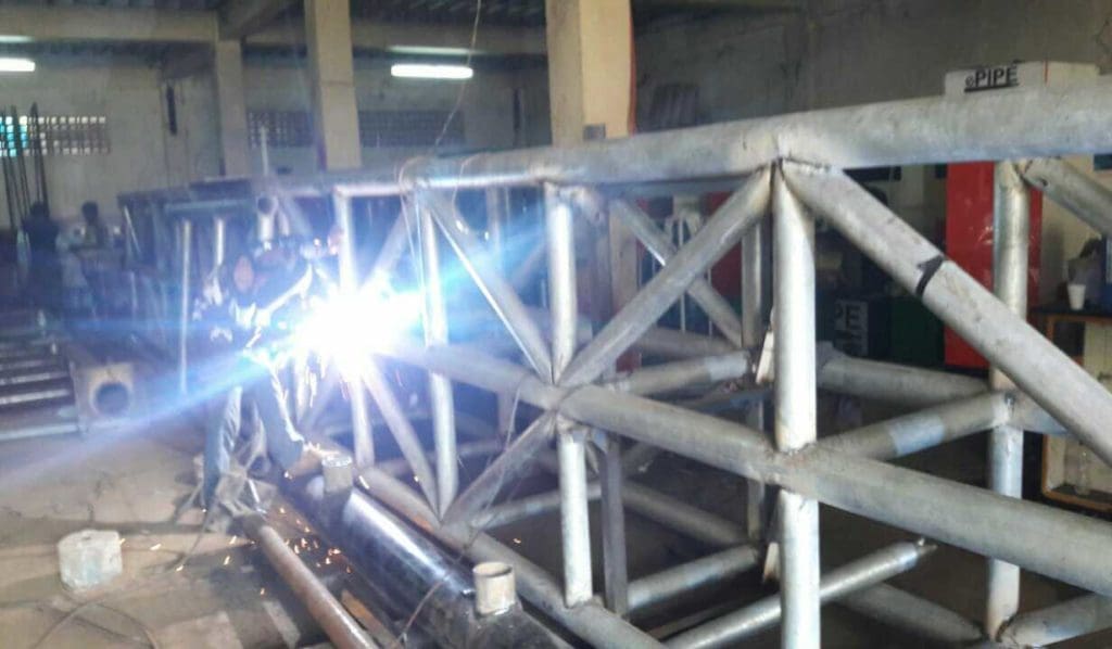 LED signage welding in industrial workshop, pipes and machinery visible, Ortigas location by M&G Global Ads.
