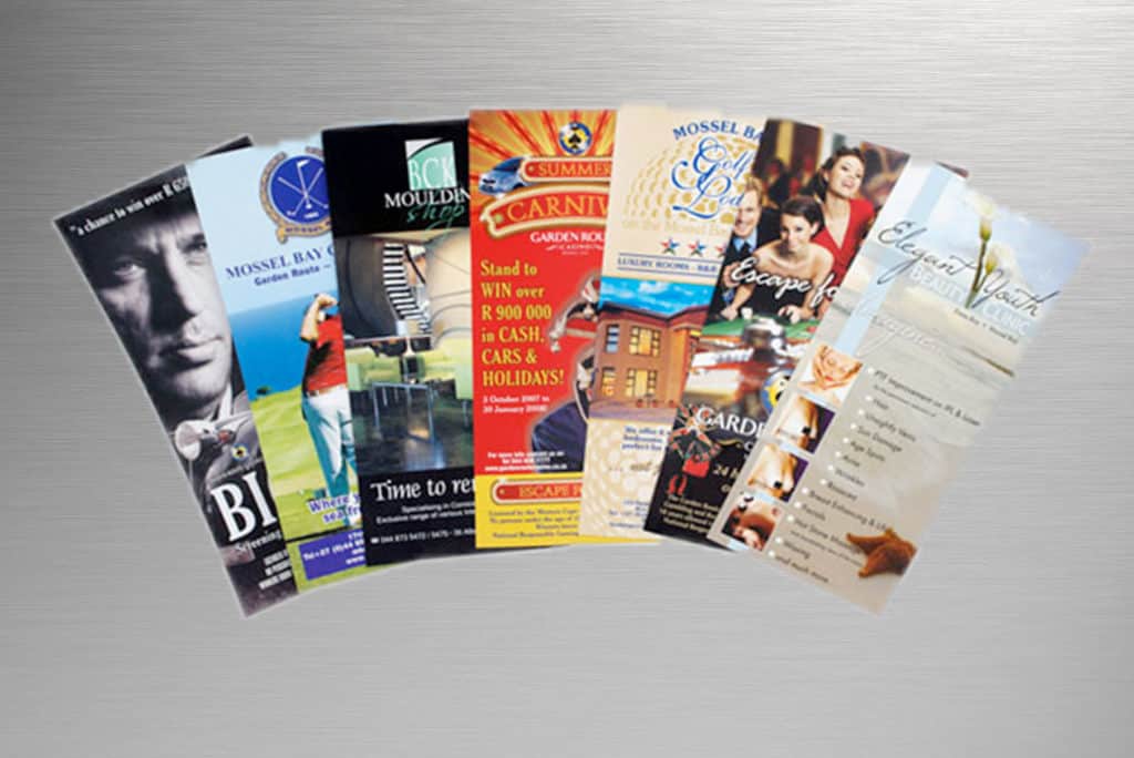Indoor signage brochures and flyers for various clients, displayed on metal surface in Makati, by M&G Global Ads.
