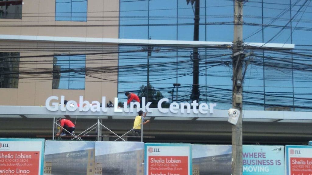 Acrylic signage installation for Global Link Center in Makati, workers on scaffolding, by M&G Global Ads.