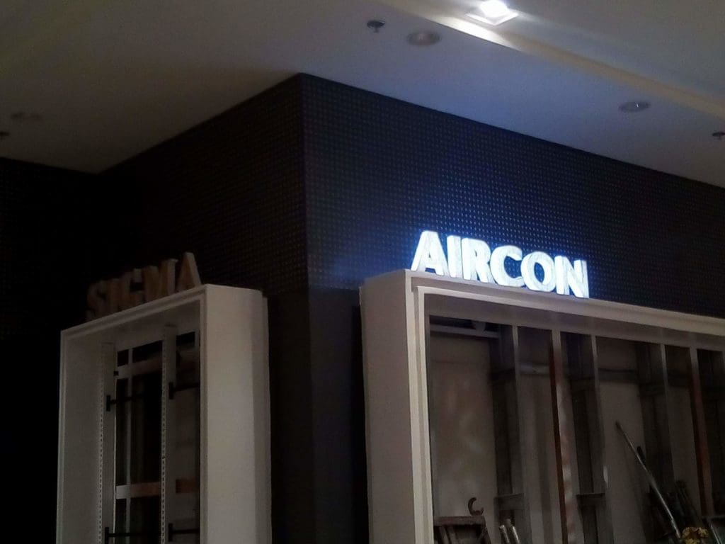 Indoor LED AIRCON signage and SIGMA acrylic sign installation in Makati with shelving below, by M&G Global Ads.