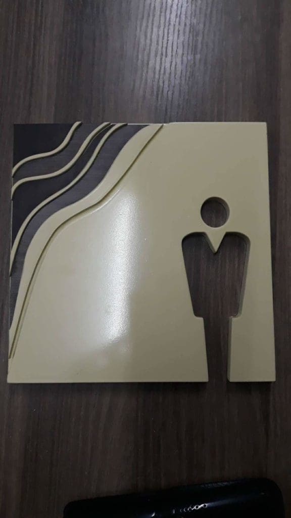 Acrylic restroom signage with person icon, three curved lines, on dark wood in Makati by M&G Global Ads.