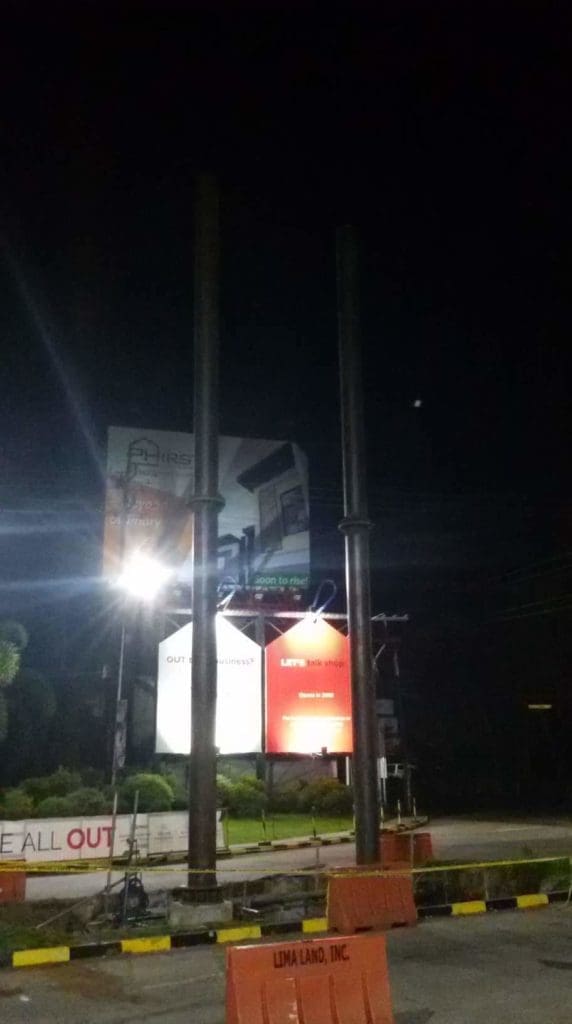 Metal billboard structures for advertising on a Makati roadside at night, construction barriers visible, by M&G Global Ads.