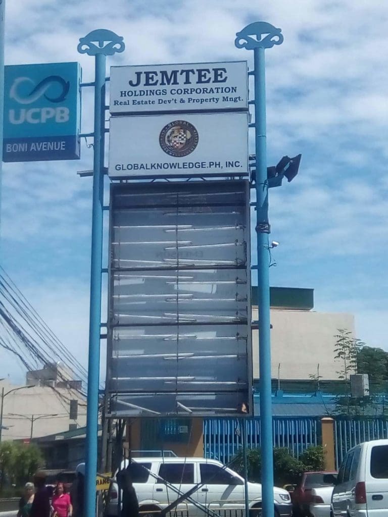Outdoor signpost signage for JEMTEE Holdings Corporation in Makati, with UCPB bank nearby, by M&G Global Ads.