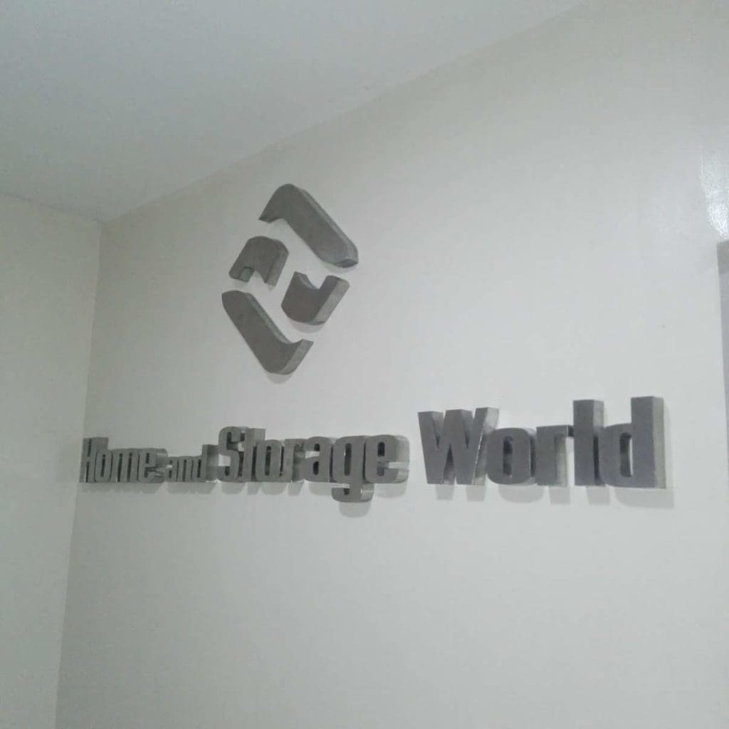 Silver 3D stainless signage for Home and Storage World with geometric logo in a Makati business interior by M&G Global Ads.