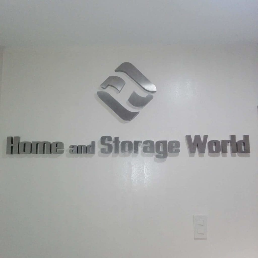 Silver 3D acrylic signage for Home and Storage World in Makati, featuring geometric logo on white wall by M&G Global Ads.