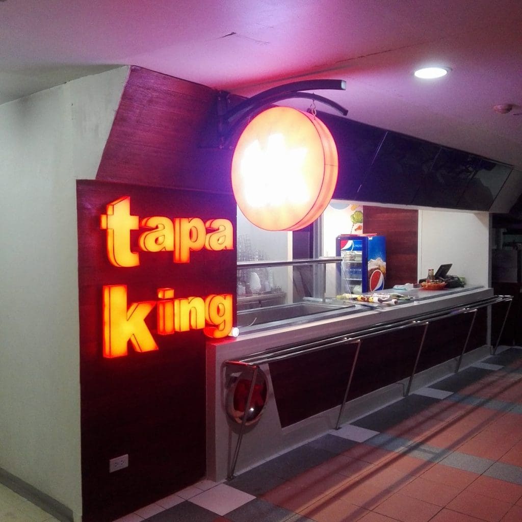 Tapa King LED signage and acrylic overhead sign at a restaurant counter in Makati, food prep area visible—by M&G Global Ads.