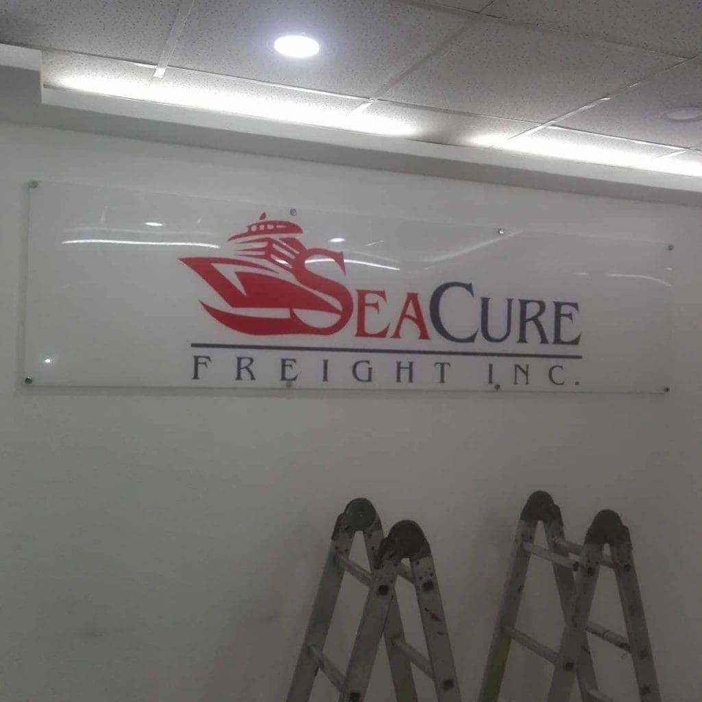Acrylic metallic signage for SeaCure Freight Inc. with logo in a well-lit Makati room, ladders in front, by M&G Global Ads.