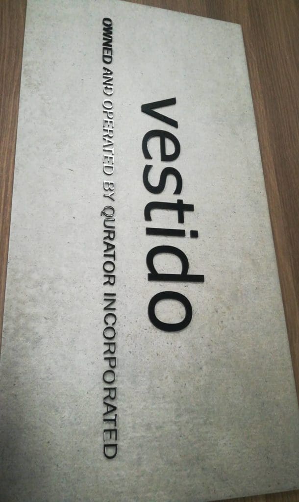 Acrylic signage for Qurator Incorporateds vestido on wood surface in Quezon City by M&G Global Ads.