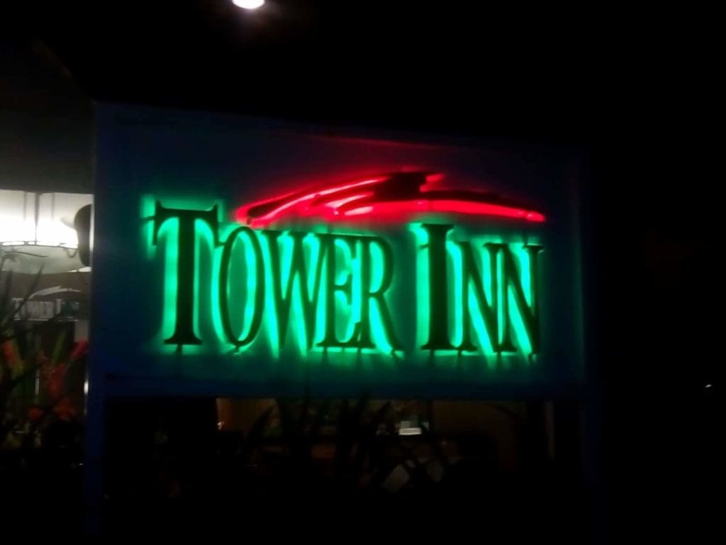 Acrylic outdoor signage for TOWER INN in green letters with red curved design, night view in Makati by M&G Global Ads.