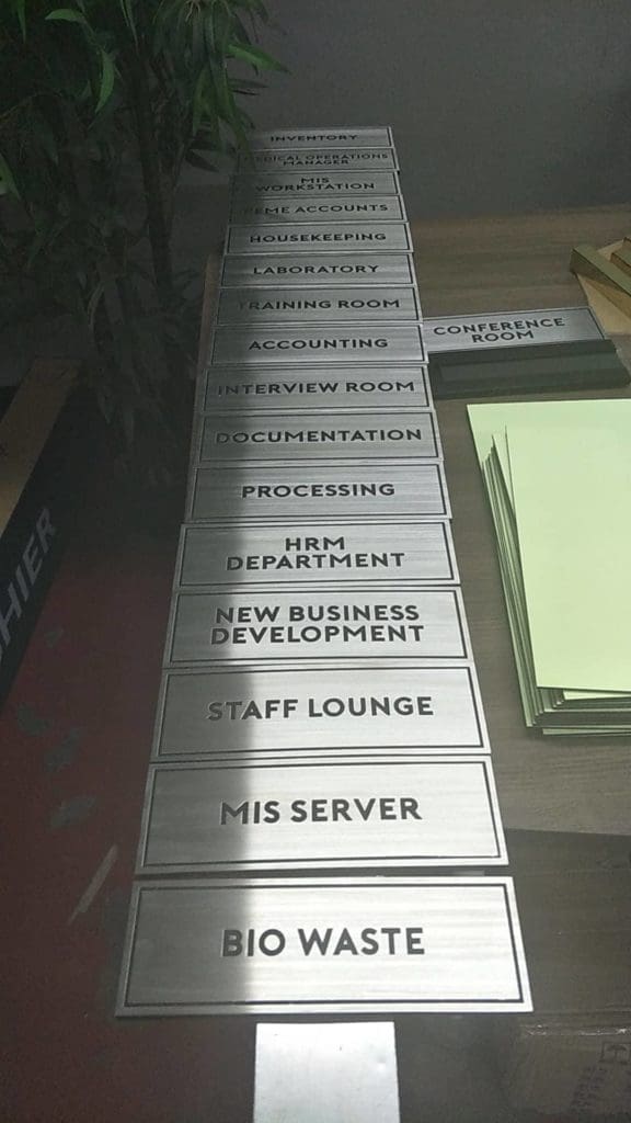 Metallic office door signage for various departments displayed on a table in Makati by M&G Global Ads.