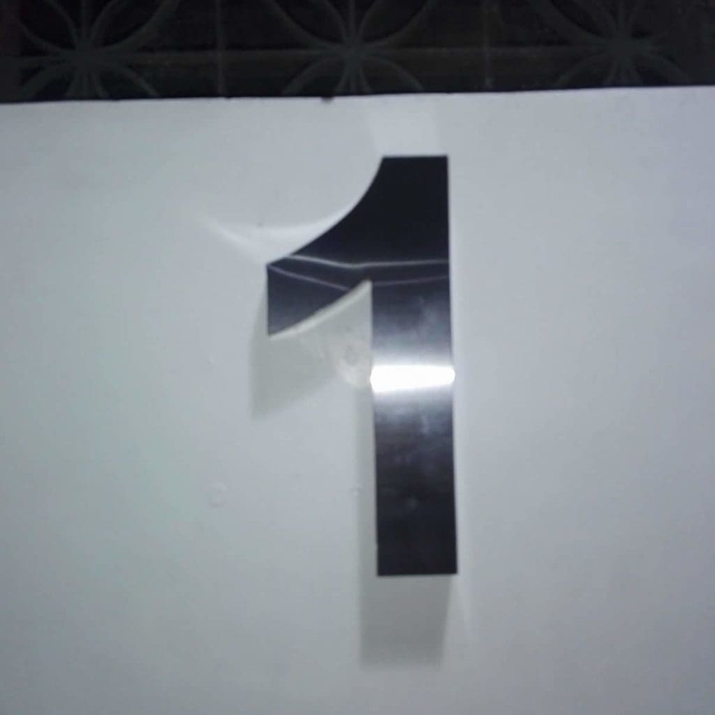 Custom metallic number one wall signage in Makati with bent upper left corner detail by M&G Global Ads.