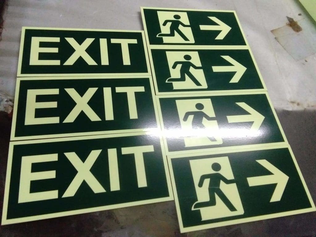 Indoor EXIT and emergency exit signs for office safety in Makati, dark background with light text by M&G Global Ads.