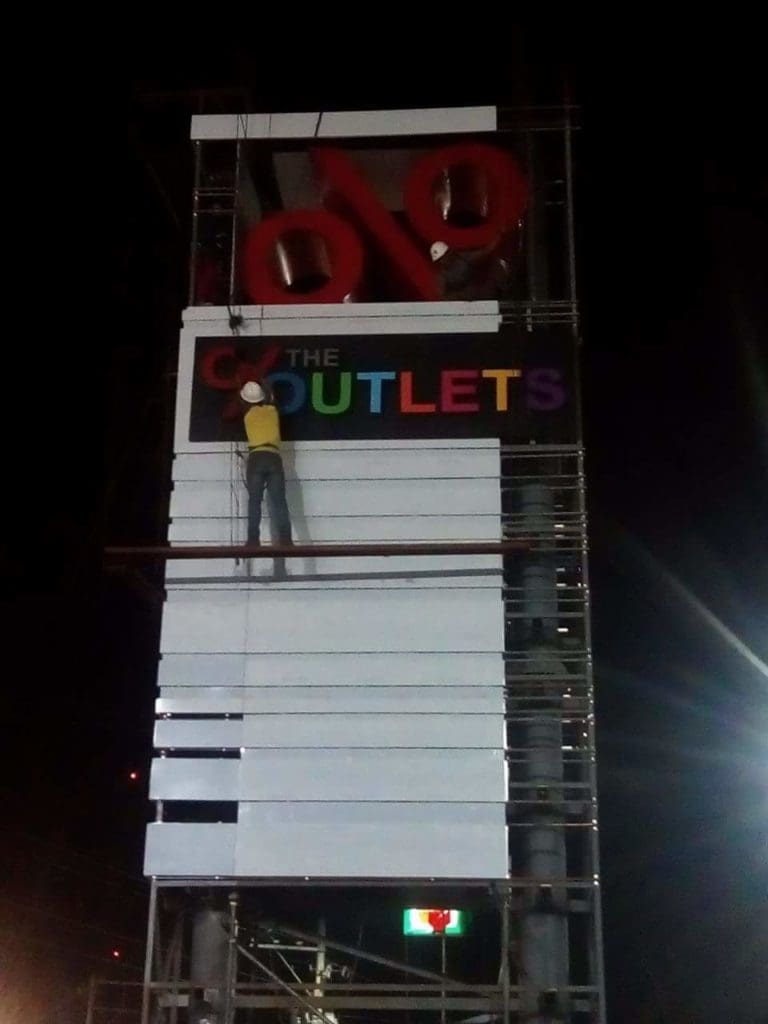Outdoor mall signage installation for THE OUTLETS in Ortigas with colorful letters and red percent, by M&G Global Ads.