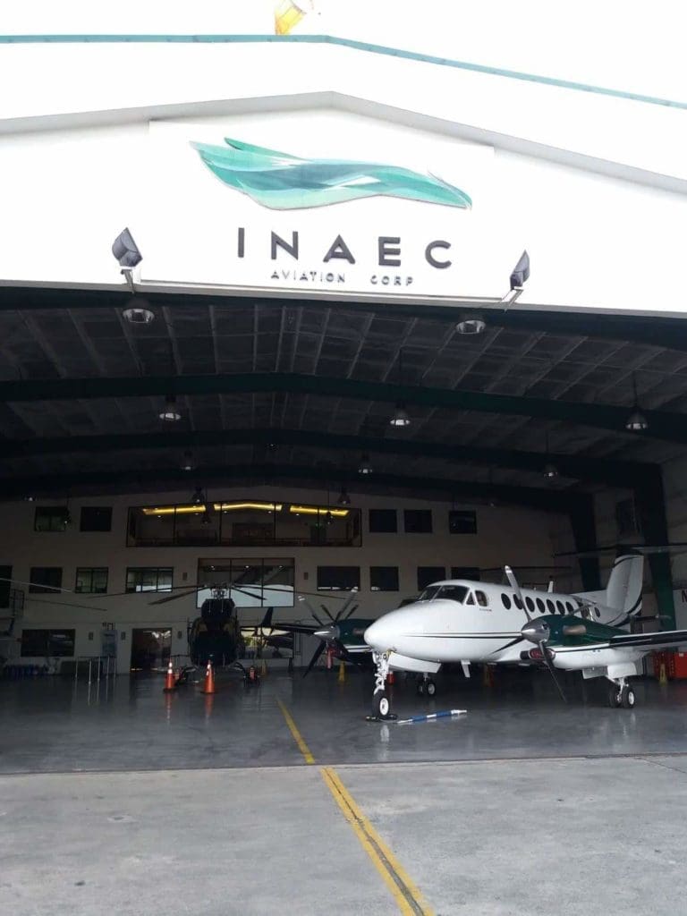 Metallic building signage for INAEC AVIATION CORP on a hangar in Pasig by M&G Global Ads. Planes and helicopter parked inside.