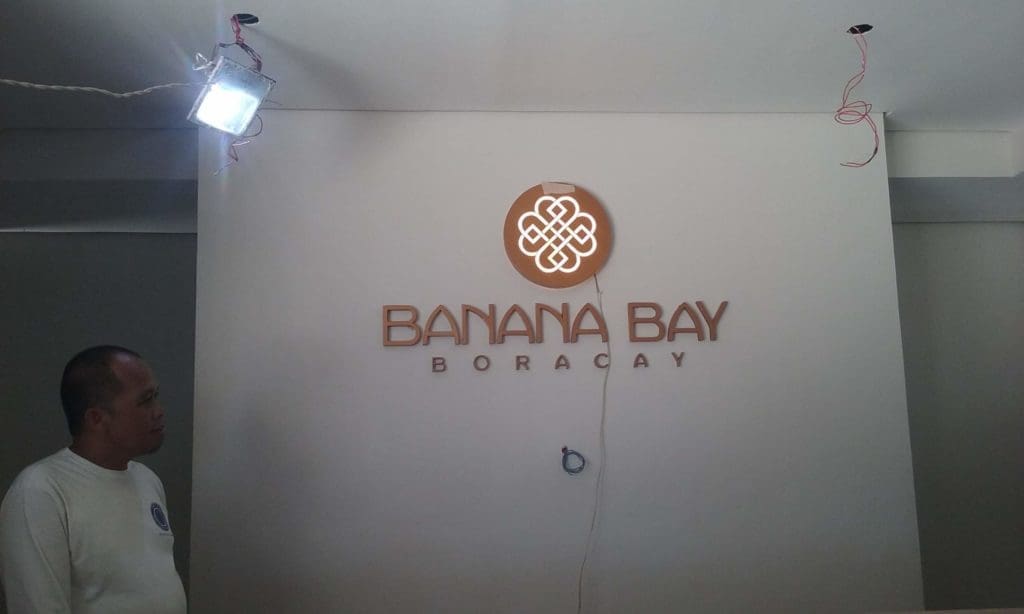 Acrylic signage for Banana Bay Boracay client shown in Makati, gold logo and emblem, installation by M&G Global Ads.