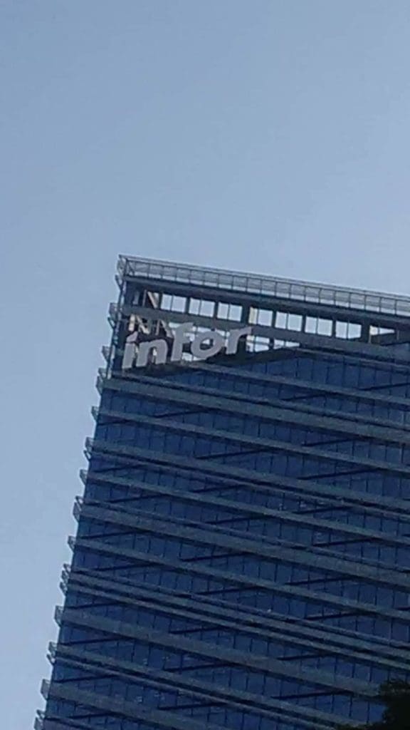 Damaged metallic building signage reading Inter atop modern glass office in Makati, clear sky, by M&G Global Ads.