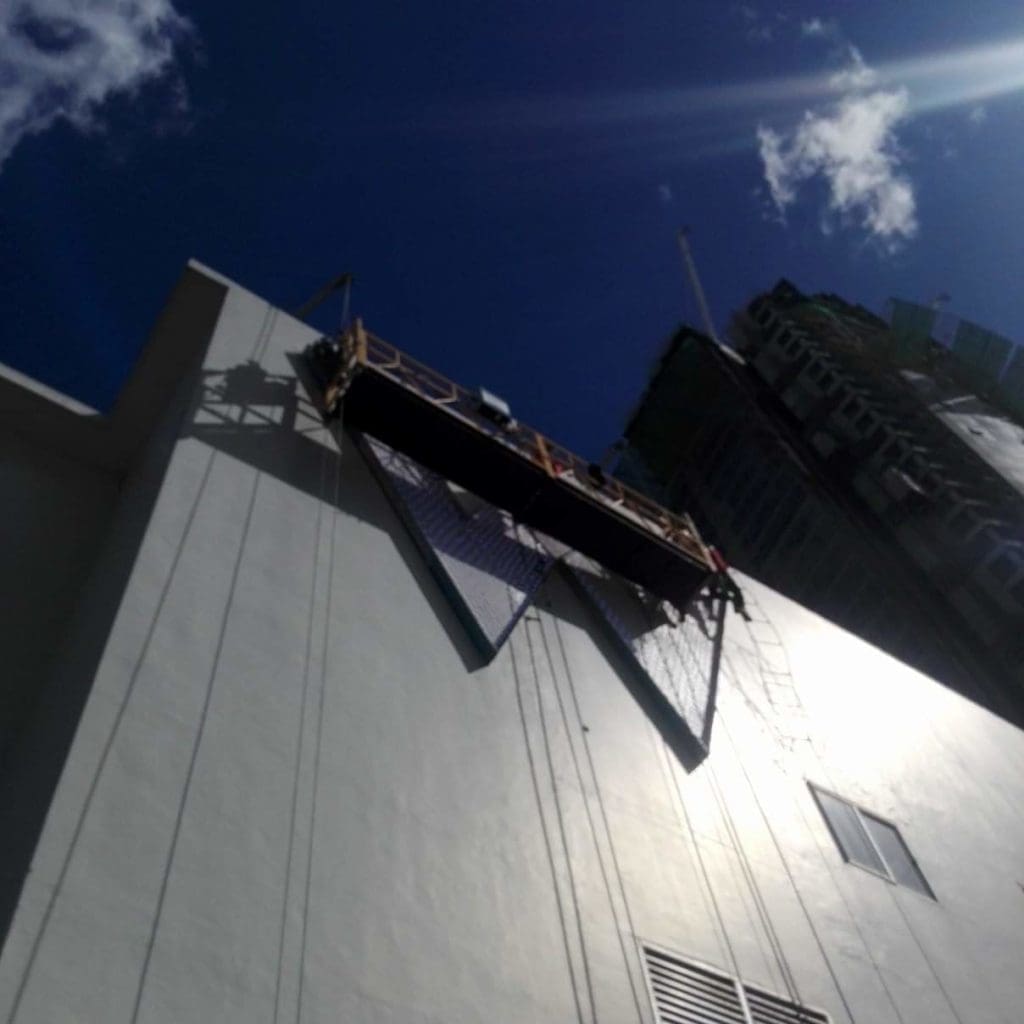 High-rise billboard installation on a tall building in Makati with scaffold, ropes, and safety nets by M&G Global Ads.
