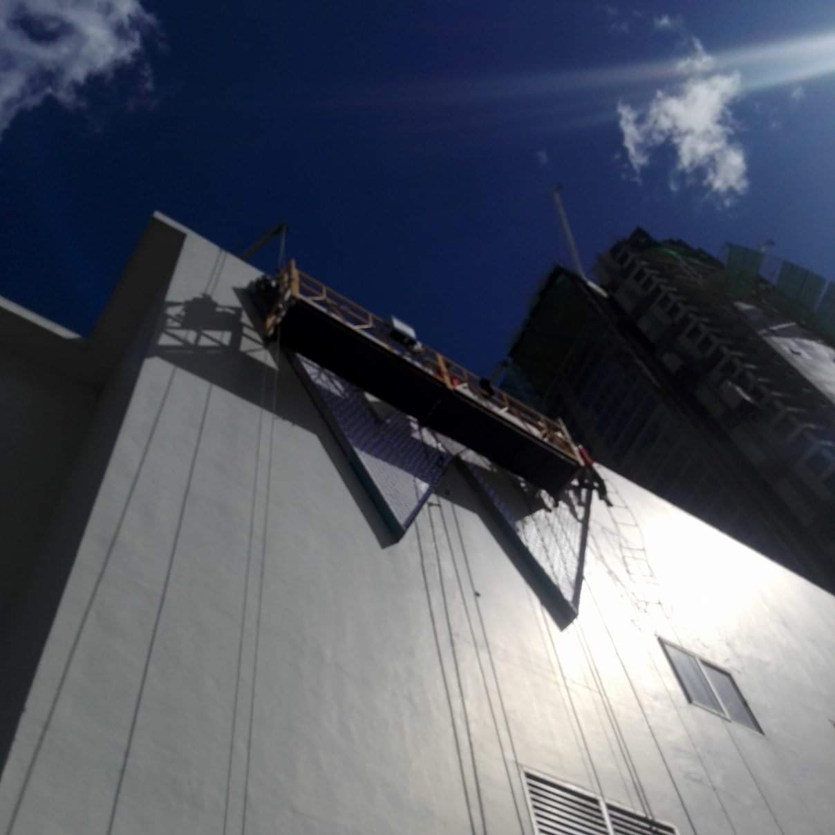 High-rise billboard installation on a tall building in Makati with scaffold, ropes, and safety nets by M&G Global Ads.
