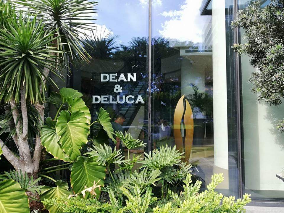 Dean & Deluca bold outdoor signage on glass storefront with tropical plants in BGC, Metro Manila by M&G Global Ads.