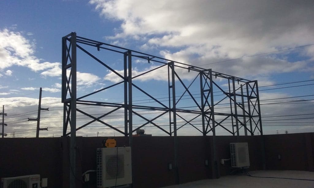 Empty metal billboard signage frame on rooftop with AC units in Pasig, cloudy sky view by M&G Global Ads.