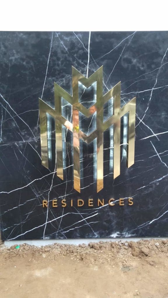 brass RESIDENCES signage for development in Makati with gold geometric building shapes, by M&G Global Ads.