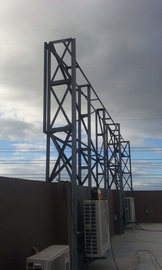 LED billboard frame installation on rooftop in Ortigas, beside AC units and power cables, cloudy sky, by M&G Global Ads.