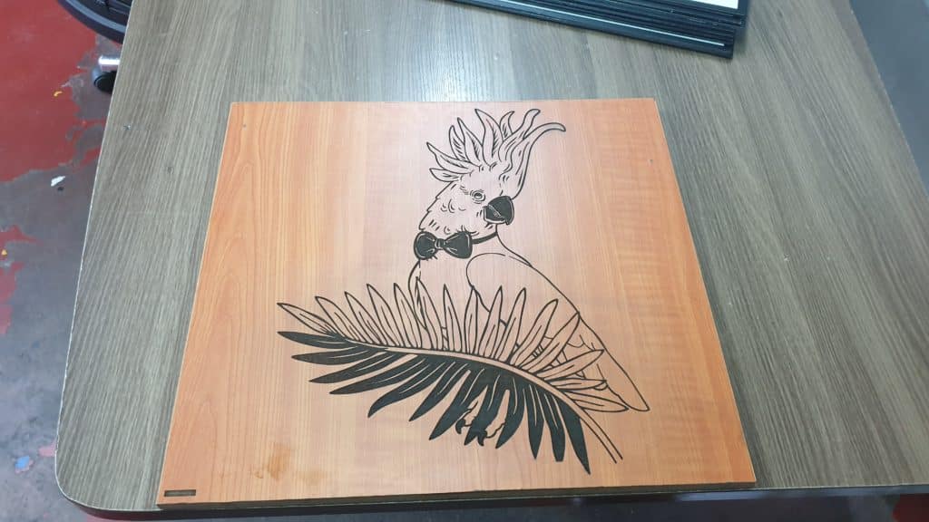 Acrylic indoor signage mockup for a Quezon City client featuring a cockatoo and tropical leaf on wood by M&G Global Ads.
