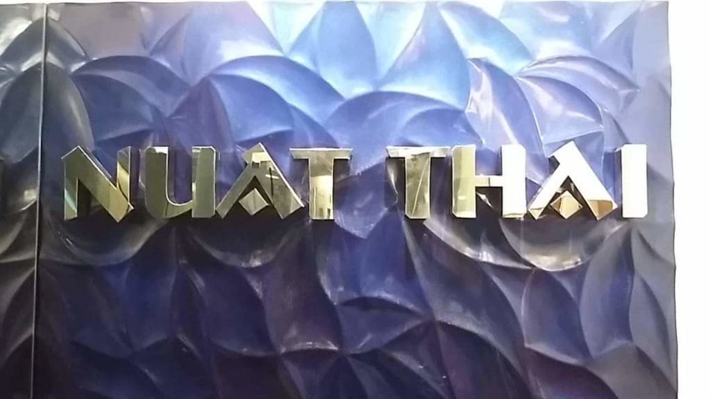 NUAT THAI spa metallic signage with silver letters on a wavy blue background in Makati by M&G Global Ads.