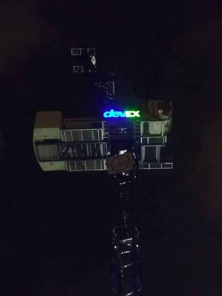 Illuminated acrylic devEX signage in blue and green on crane cabin, Ortigas Metro Manila at night by M&G Global Ads.