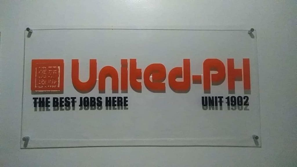 Acrylic wall signage for United-PH in Makati, bold orange letters and black text, with four fasteners by M&G Global Ads.